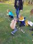 Dzieci układają na trawie ziemniaki w rzędzie.