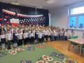 Dzieci z wszystkich grup stoją na tle dekoracji o Polsce i śpiewają hymn.