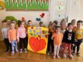 Dzieci stoją w grupie trzymając plakat z namalowanym pomarańczowym sercem.