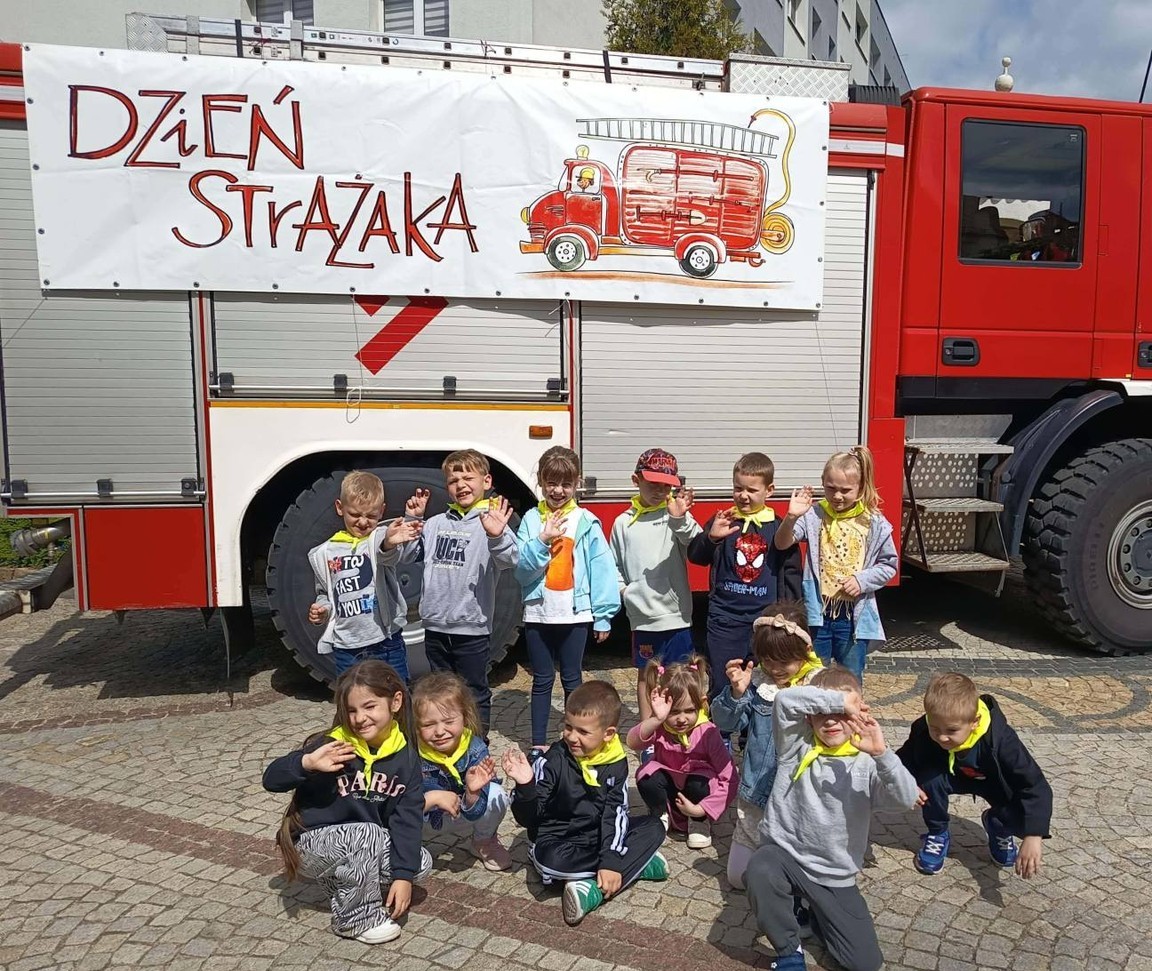 Dzieci stoją w grupie przed wozem strażackim.