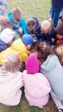 Dzieci z darów jesieni układają na dworze uśmiechniętą buzię.