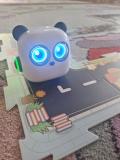 Robot edukacyjny stoi na dywanie.