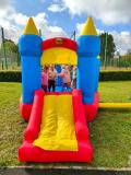Grupa dzieci stoi na dmuchańcu w kształcie zamku.