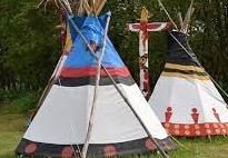 Na trawie stoją dwa namioty indiańskie.