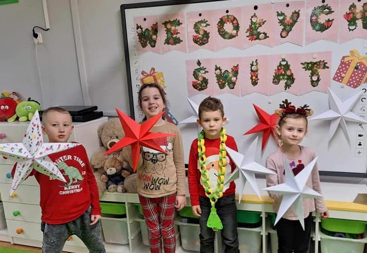 Czworo dzieci stoi trzymając w ręku własnoręcznie zrobione ozdoby bożonarodzeniowe.