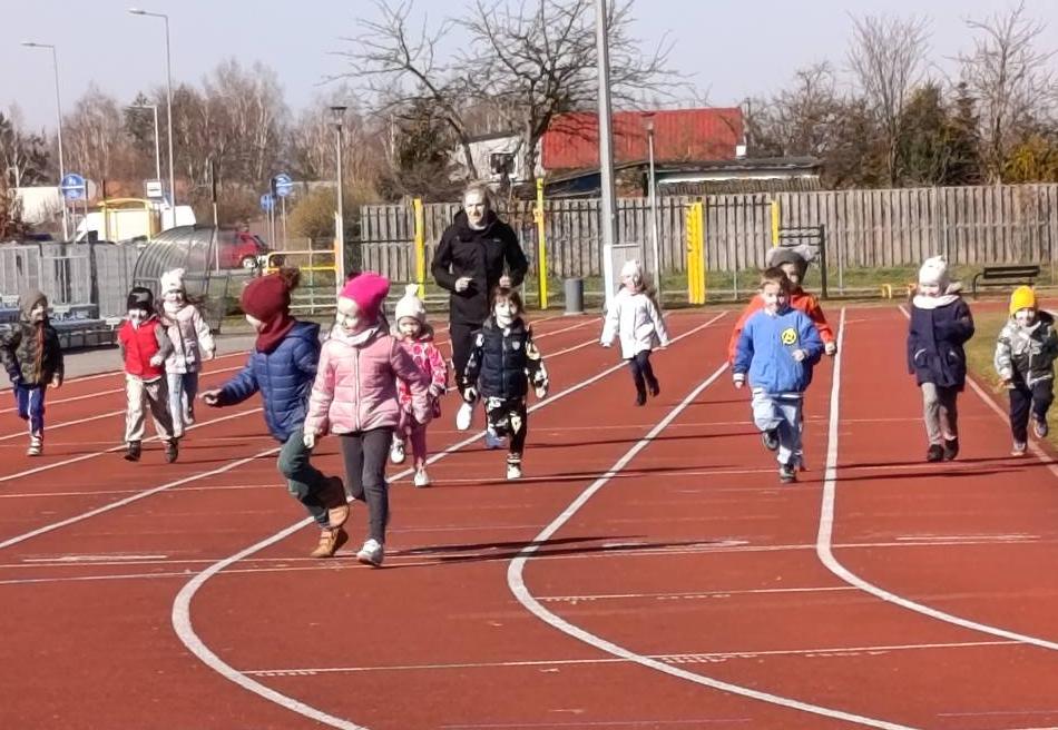 Dzieci biegną na stadionie po torze.