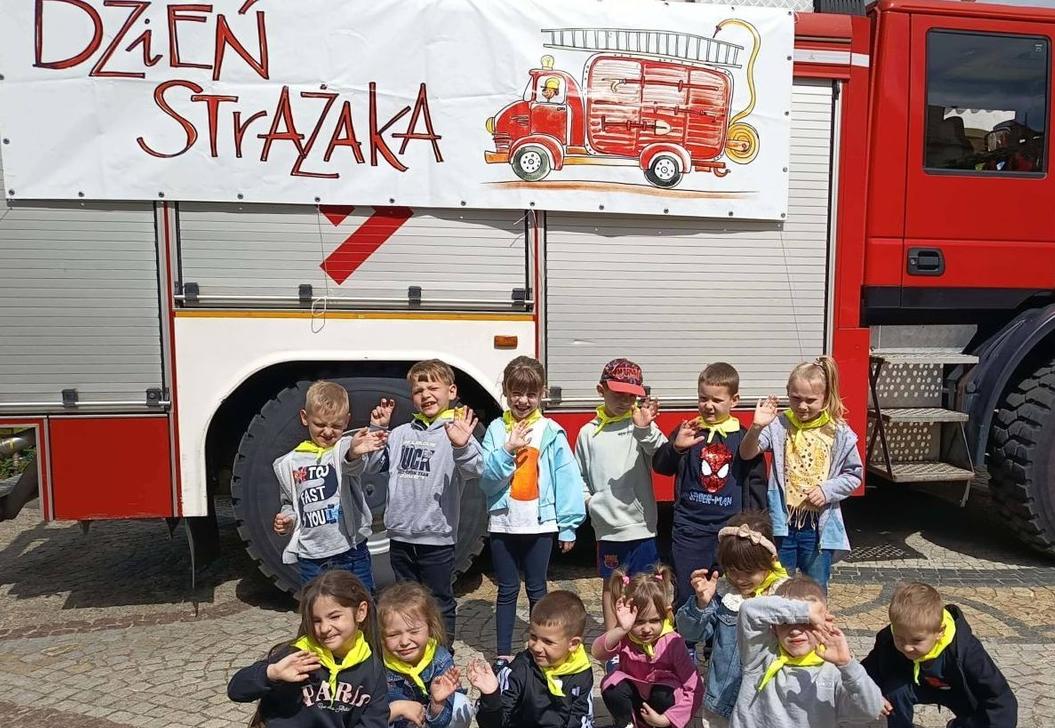 Dzieci stoją w grupie przed wozem strażackim.