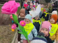 Dzieci idą w parach trzymając w rękach kolorowe kwiaty.